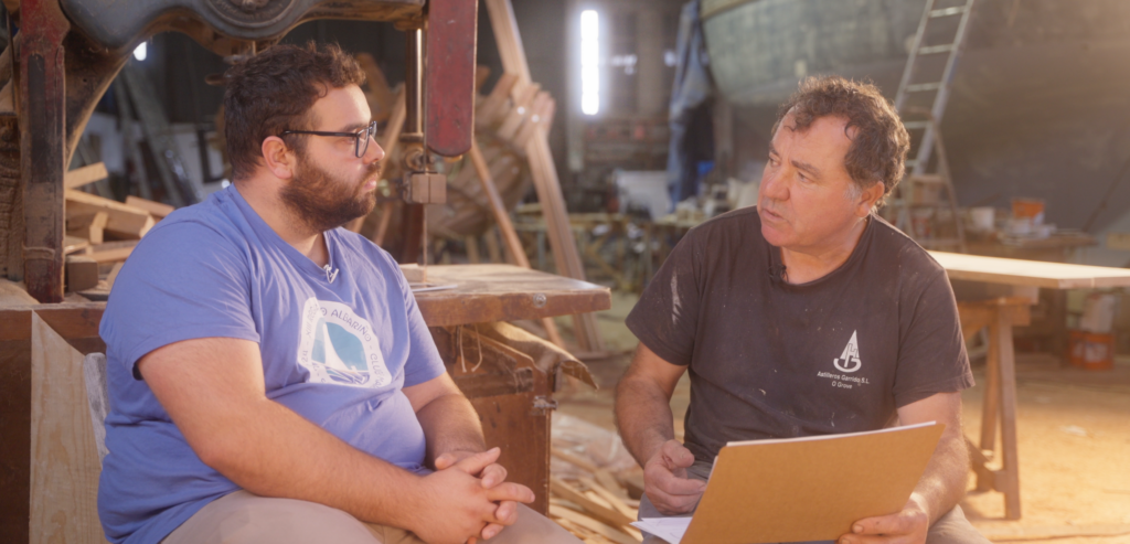 Fotograma da curta. Rubén González e Pepe Garrido falando do proceso de creación dos planos e medio casco e a importancia da Carpintería de Ribeira na nosa cultura.